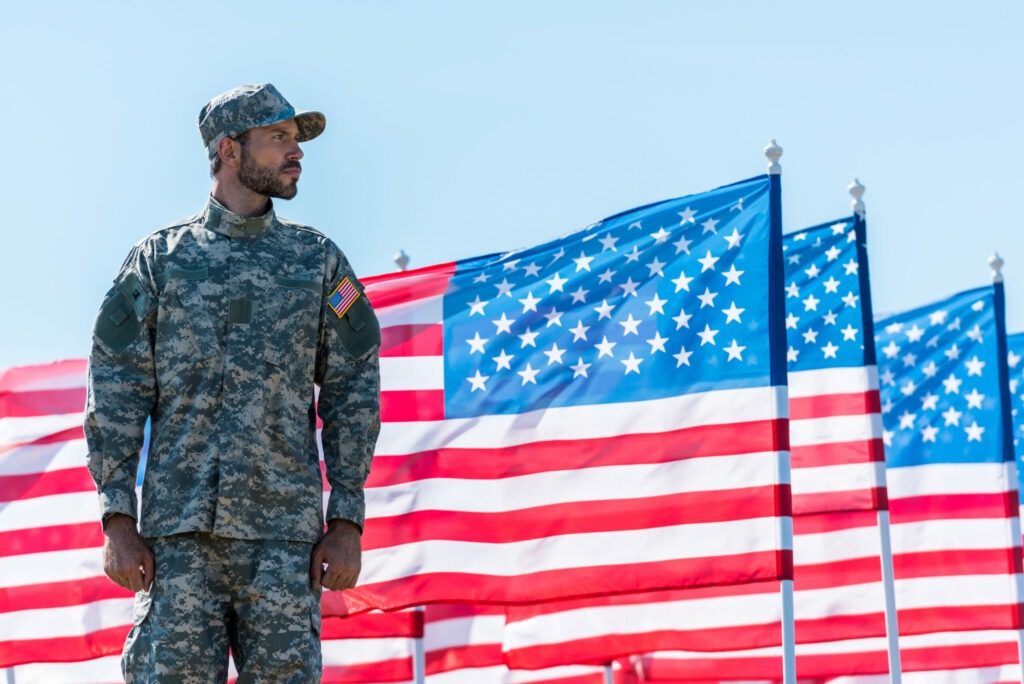 Soldier in Uniform Standing Near American Flags